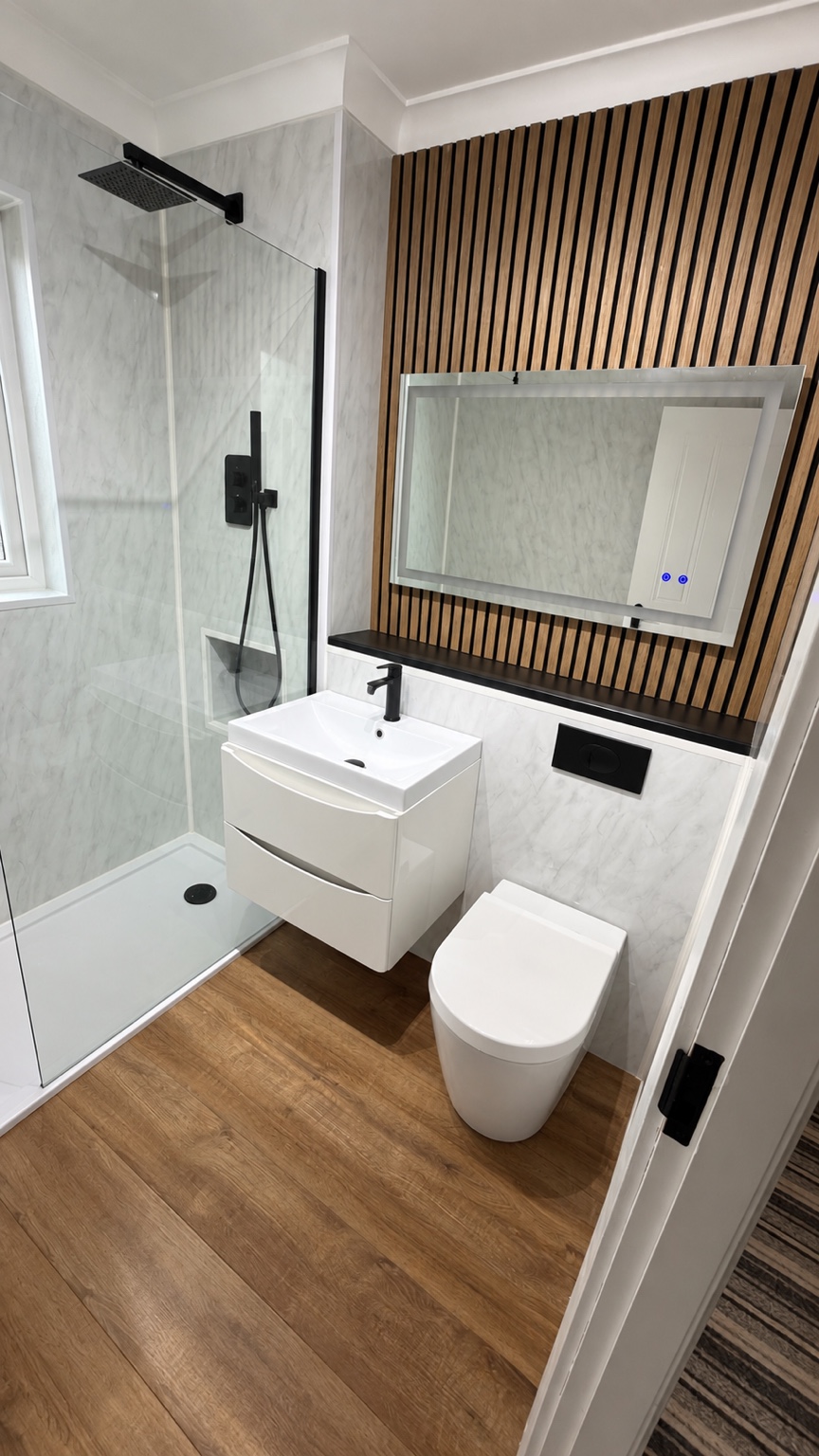 Modern shower room with black fittings, white vanity and wood-effect feature wall