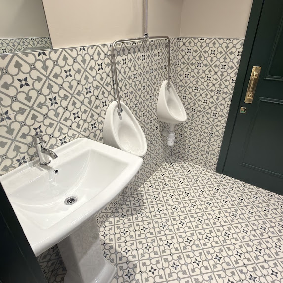 Washroom basin and two urinals with patterned wall and floor tiles